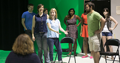 Actors take stage direction in front of green screen