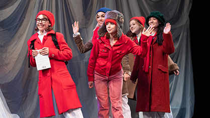 high school students perform in a play in vibrant red jackets