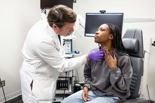 doctor applying device to patient's throat