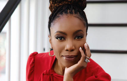 Heather Headley wears a red dress and rests her chin in her hand