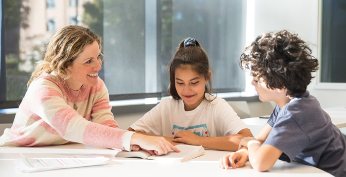 instructor showing book to 2 children